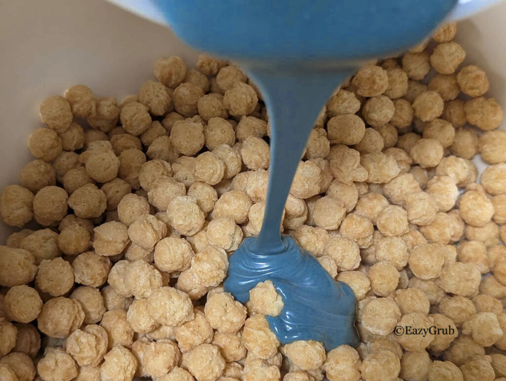 Blue/green chocolate pouring on round corn cereal.