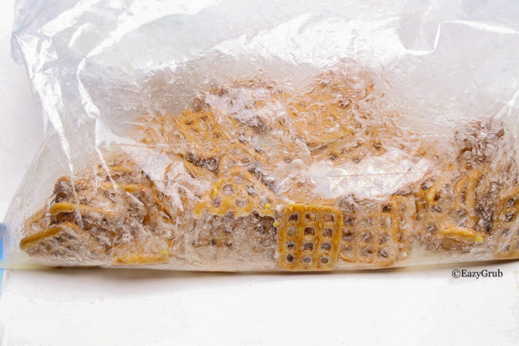 Square pretzels in a bag with seasoning.