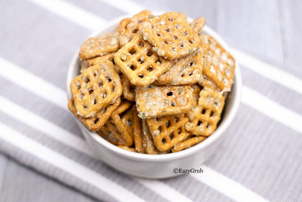 Dill ranch pretzels in a white bowl on a grey napkin.