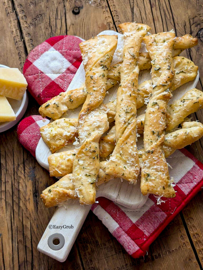 Garlic parmesan sticks on a wooden cutting board.