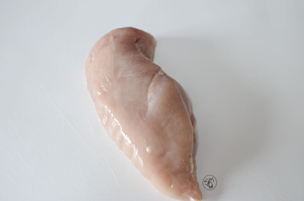 One chicken breast on a white board.
