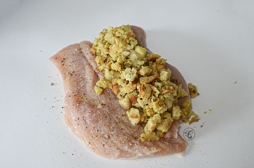A butterflied chicken breast with prepared stuffing on one side.