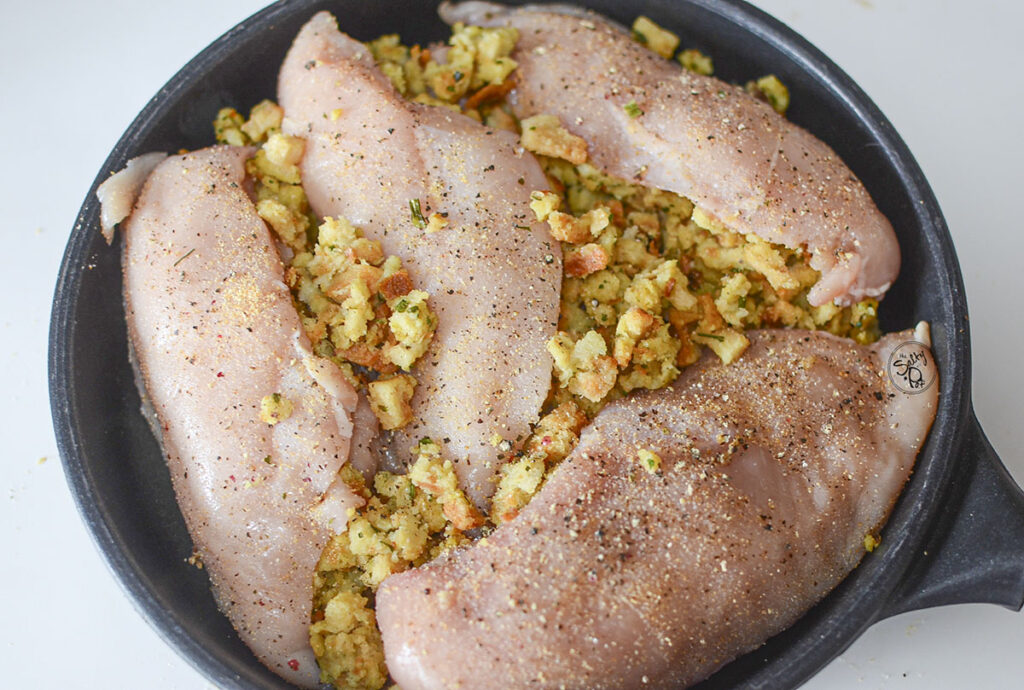 Four stuffed chicken breasts in a skillet.