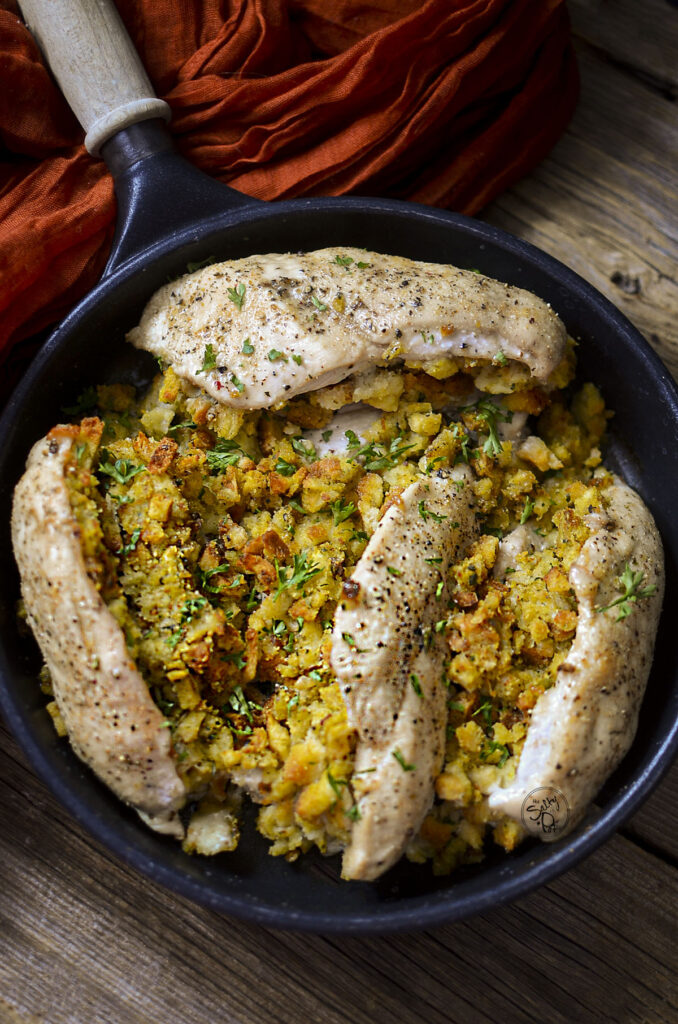 Four stuffed chicken breasts in a skillet.