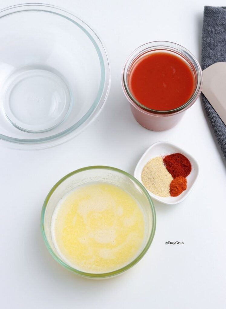 Melted butter in a glass bowl after being microwaved, slightly cooled and ready to mix with hot sauce.