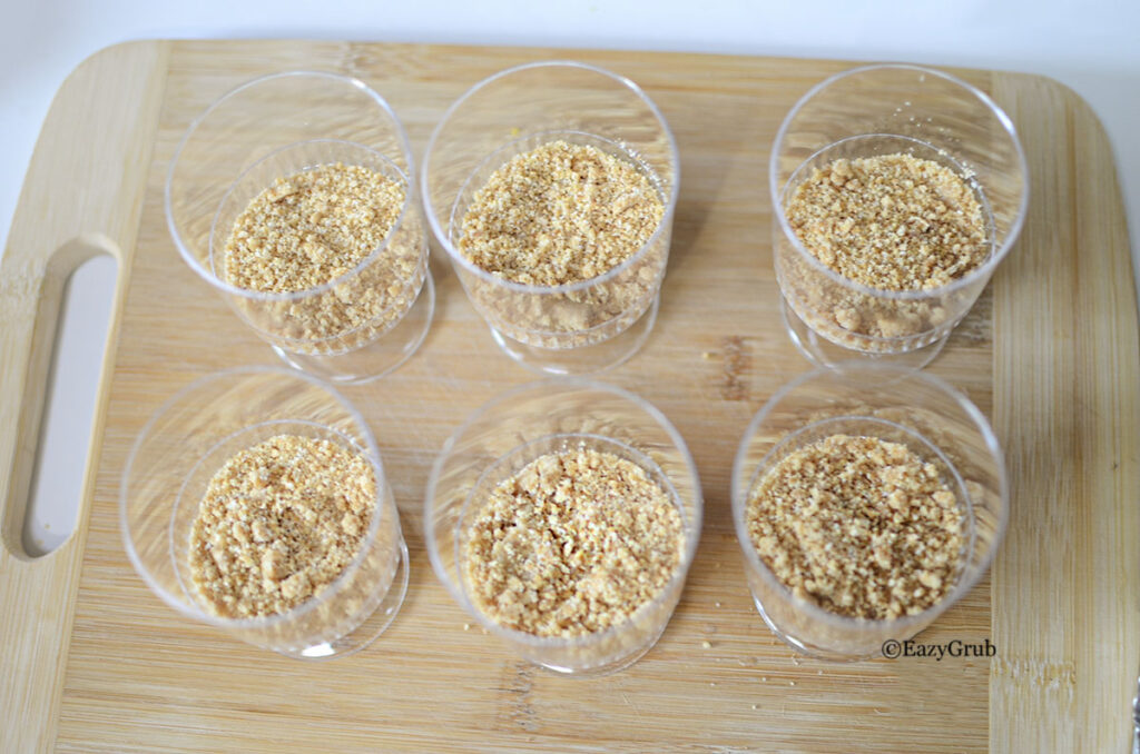 Graham cracker crumbs pressed into the bottom of small dessert cups.