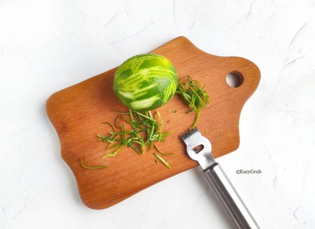 Fresh lime being zested with a fine grater for homemade lime tart filling.