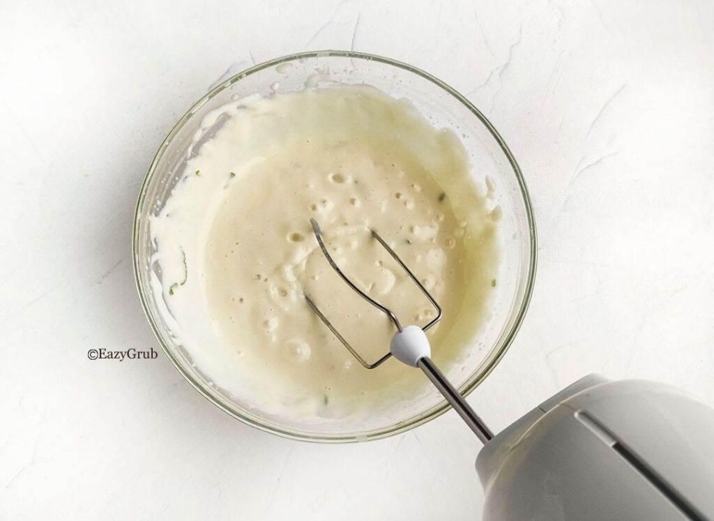Sweetened condensed milk mixed with fresh lime juice and zest in a bowl until smooth and creamy.