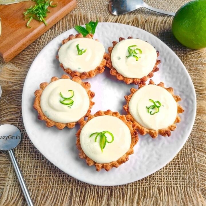 Close-up of creamy lime tart filling inside a crumbly tart shell, garnished with fresh zest.