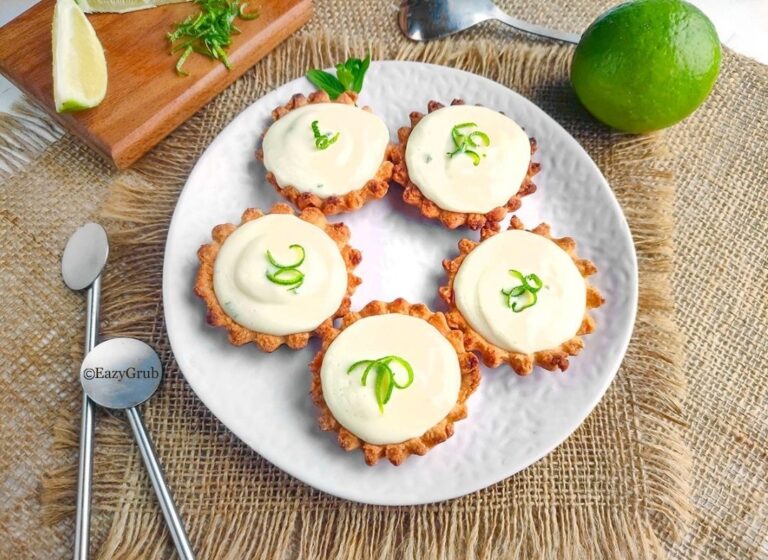 Close-up of creamy lime tart filling inside a crumbly tart shell, garnished with fresh zest.
