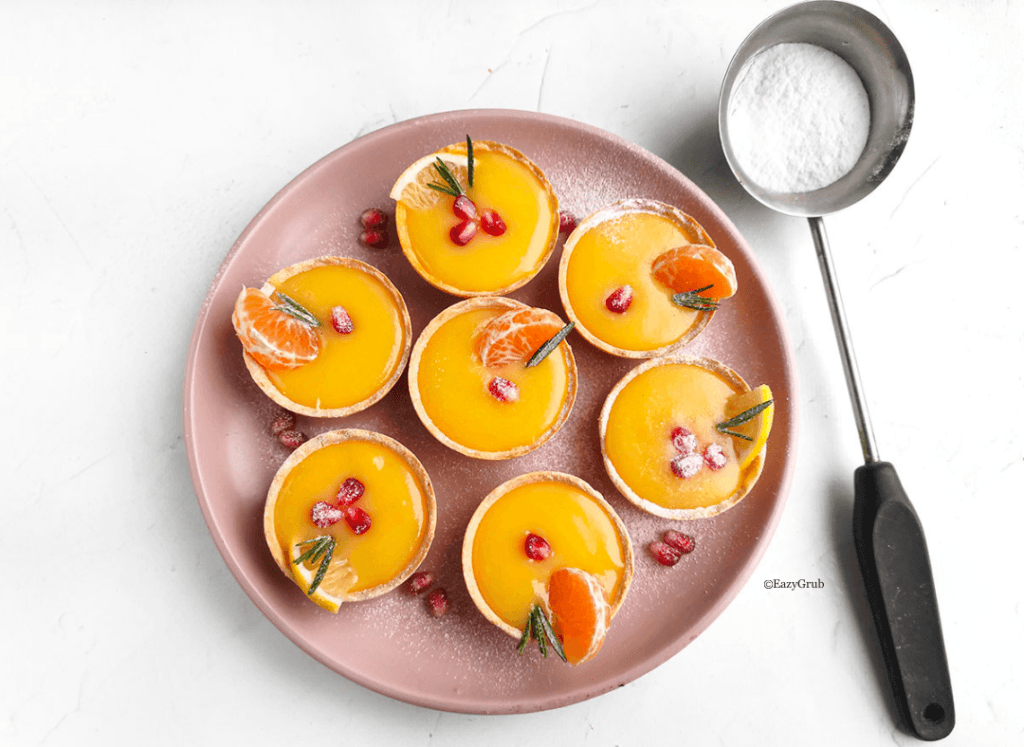 Finished lemon curd tarts arranged on a serving platter, bright yellow filling