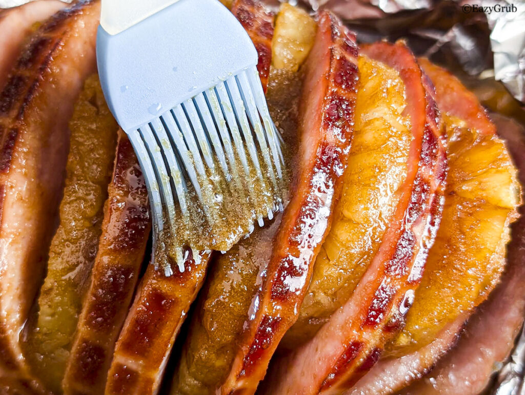 Glazing the ham before broiling.