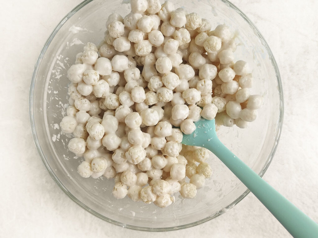 Round cereal in a bowl with a blue spatula coming out of it at the bottom right.