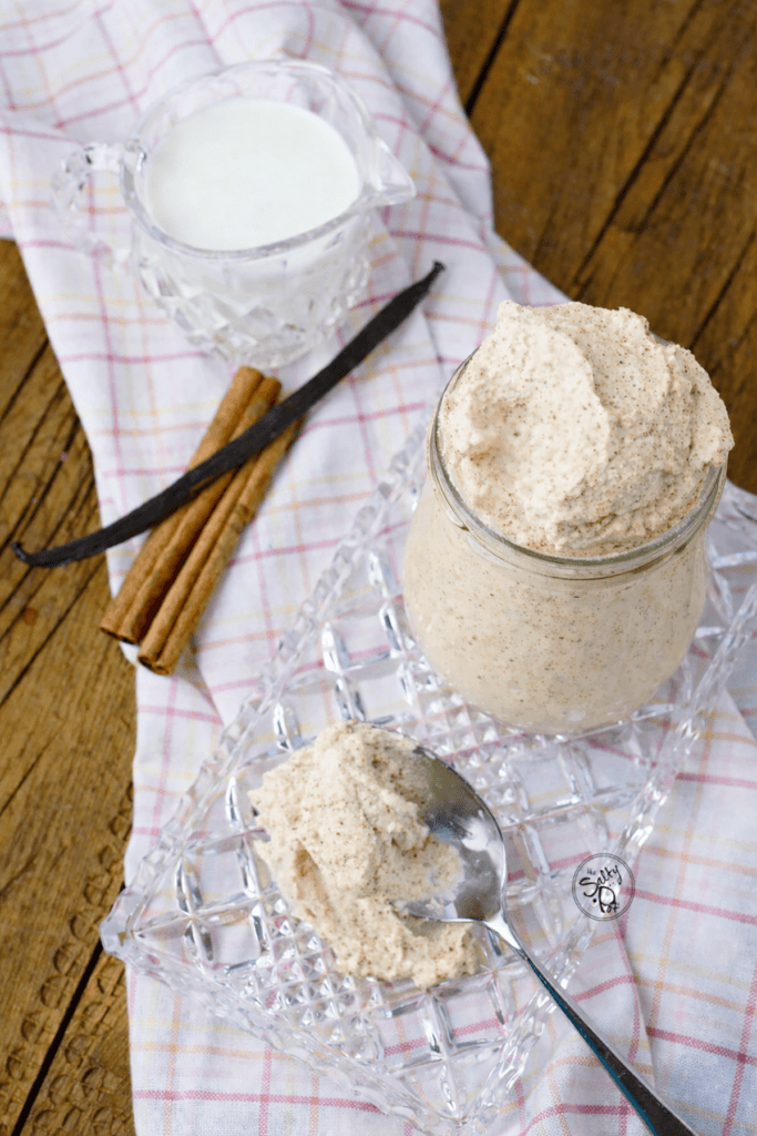 Cinnamon whipped cream on a glass plate, with some cream on a spoon on a pink and yellow checked napkin.