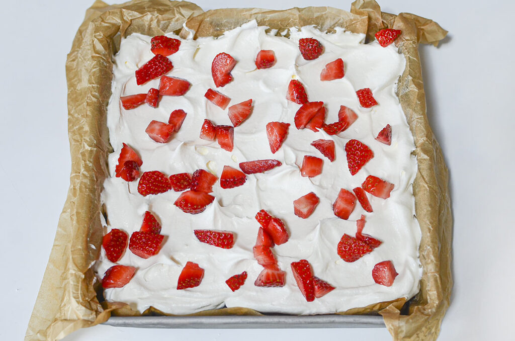 The completed strawberry Twinkie cake, topped with a thick layer of whipped topping and a generous of sliced fresh strawberries.