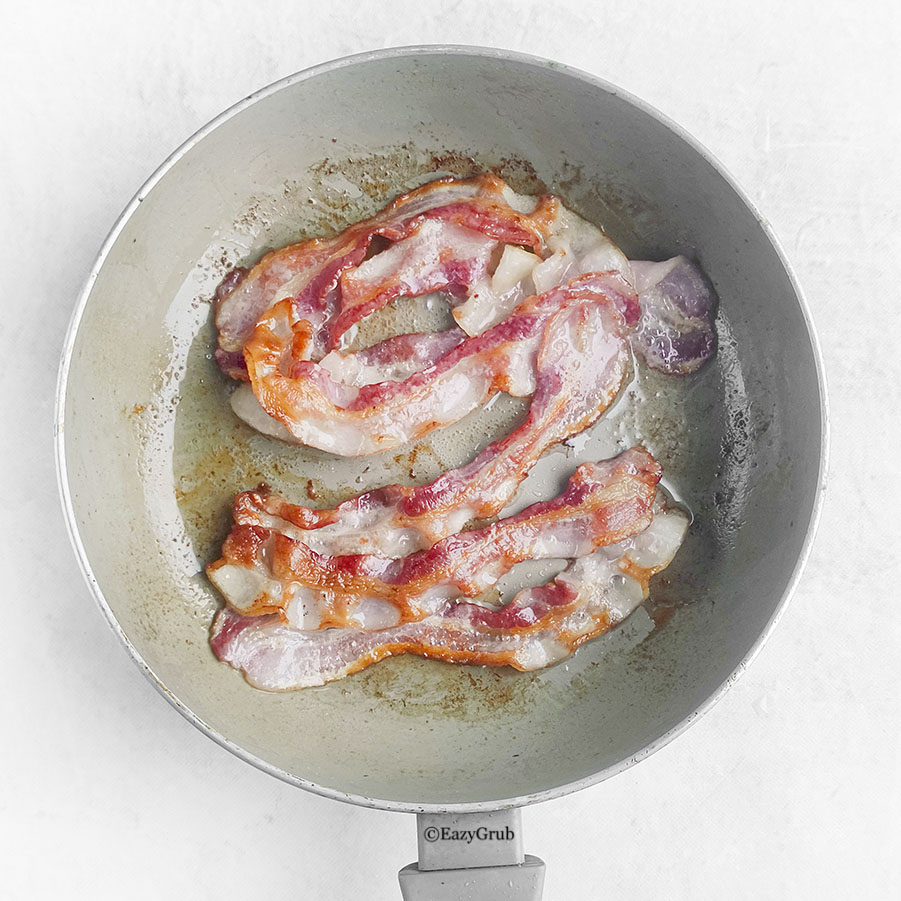 bacon strips cooking inside a skillet