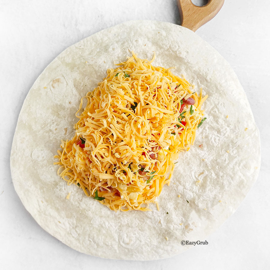 Layer of shredded cheese covering filling on an open flatbread.