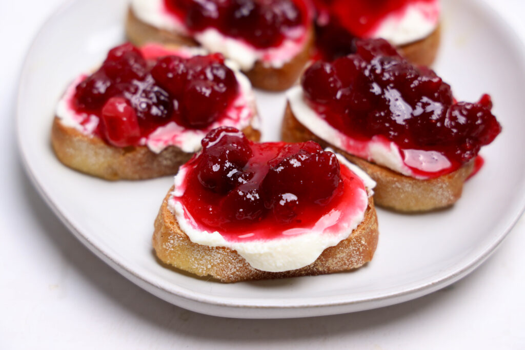 Bread slices topped with ricotta chees and cranberry sauce