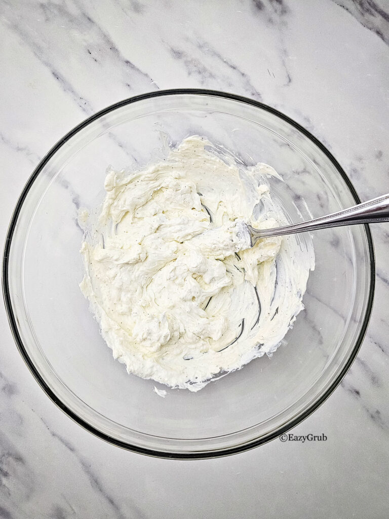 Creamy white base mixture spread inside a glass bowl with a fork.