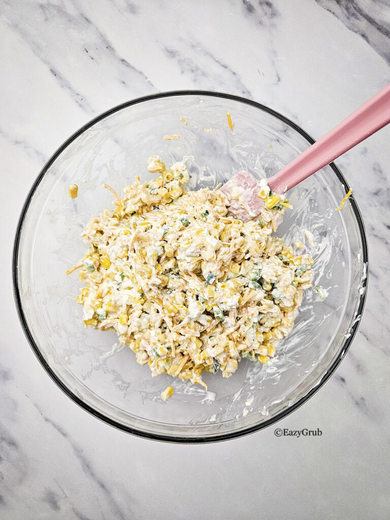 Ingredients mixed together with a spatula inside a glass mixing bowl.