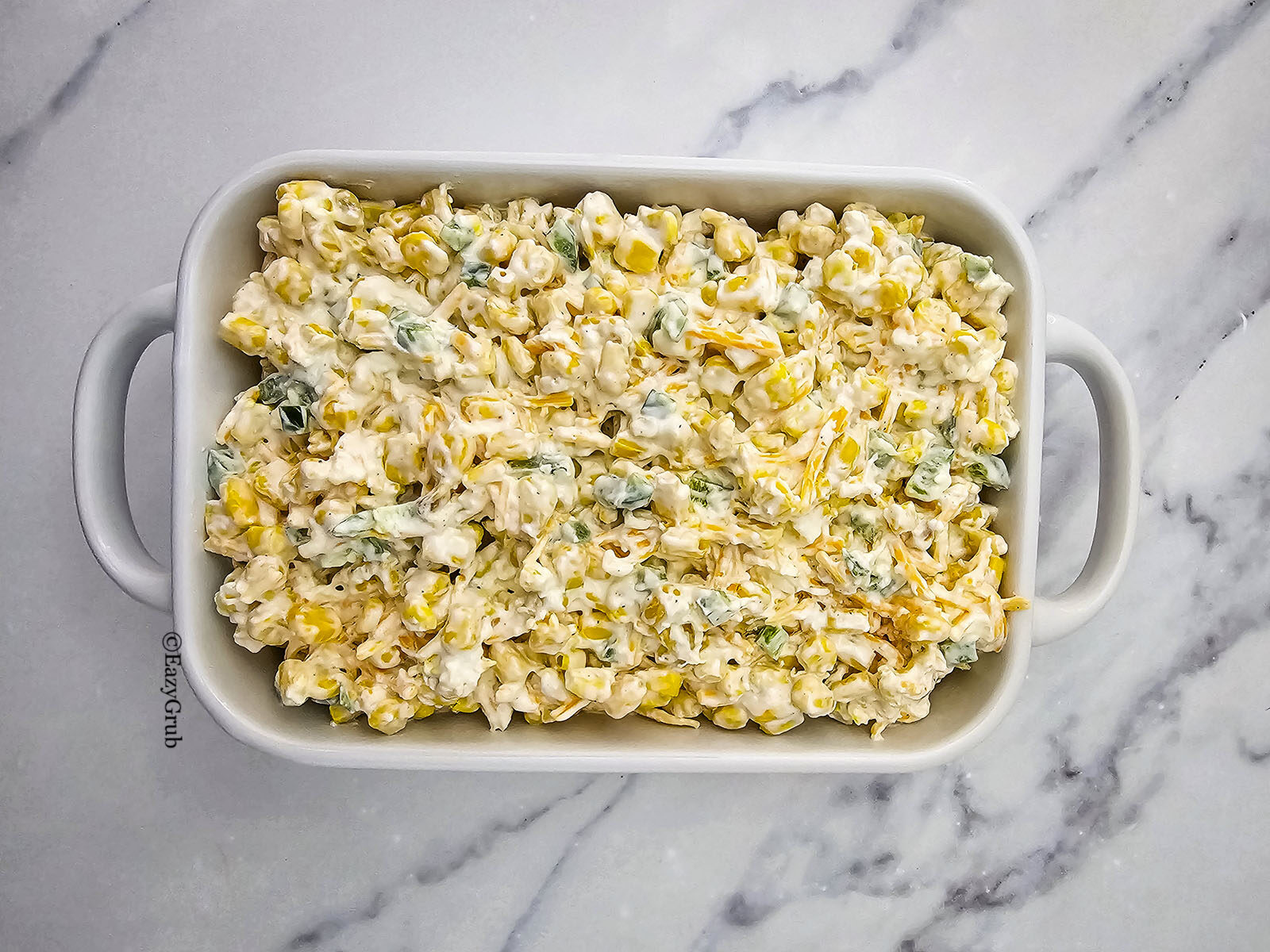 Creamy corn mixture spread evenly into a white rectangular baking dish.