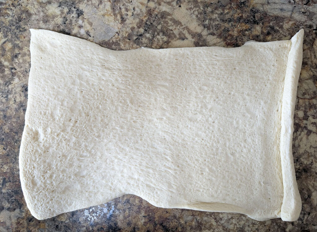 Pizza dough unrolled on the counter.