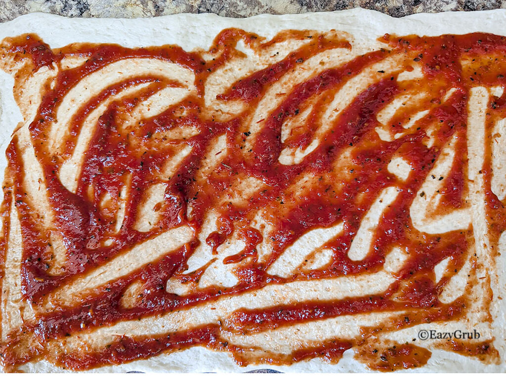 Pizza sauce spread over the top of the dough.