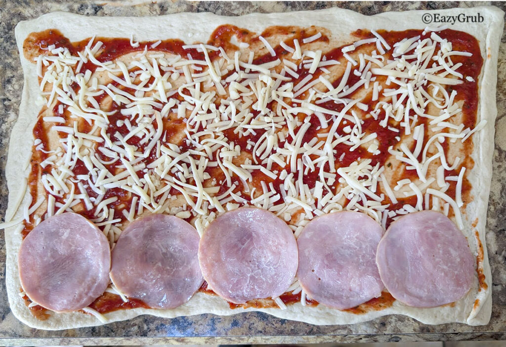Shredded cheddar and meat placed on the dough.