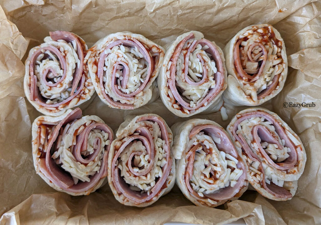 The cut rolls placed in a parchment lined baking dish.