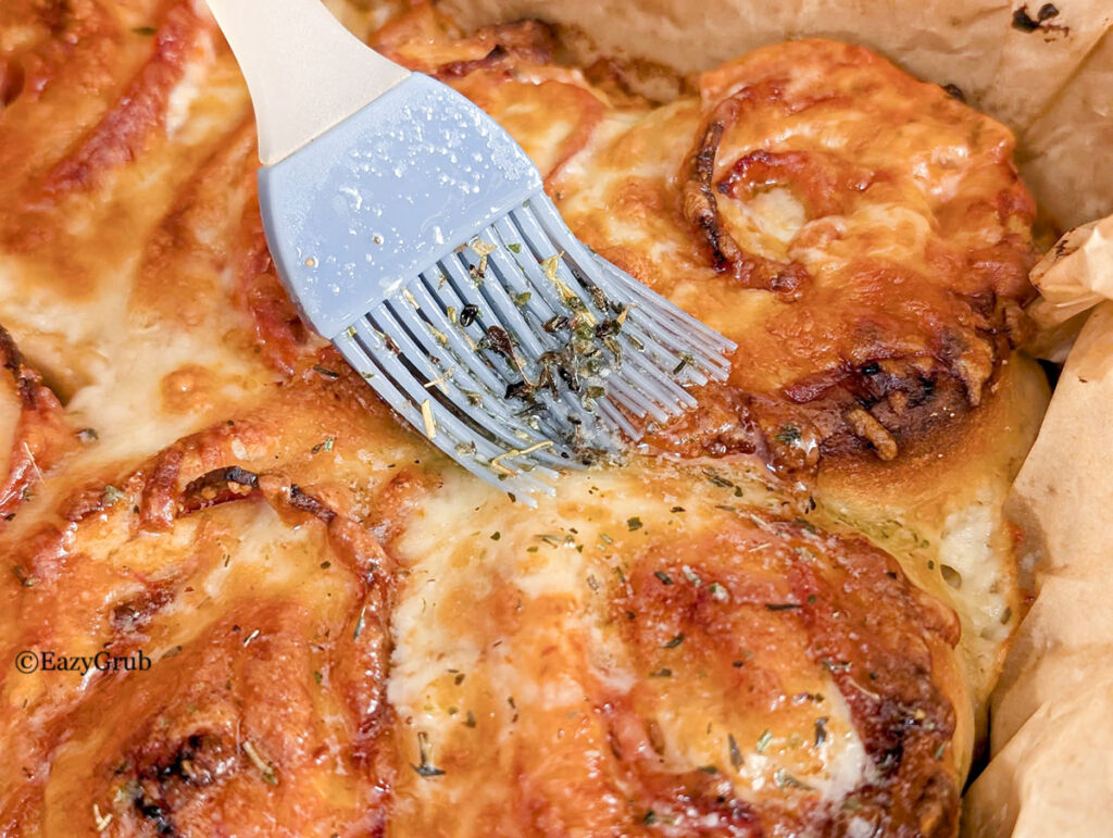 Melted butter and italian seasoning with garlic sauce brushed over top the rolls after baking.