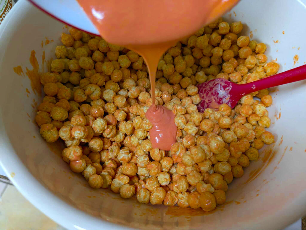 Smooth orange coating being poured over a large bowl of cereal puff